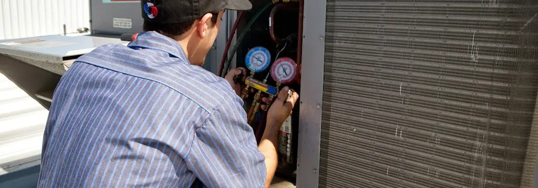 HVAC technician servicing a condenser unit in Coon Rapids